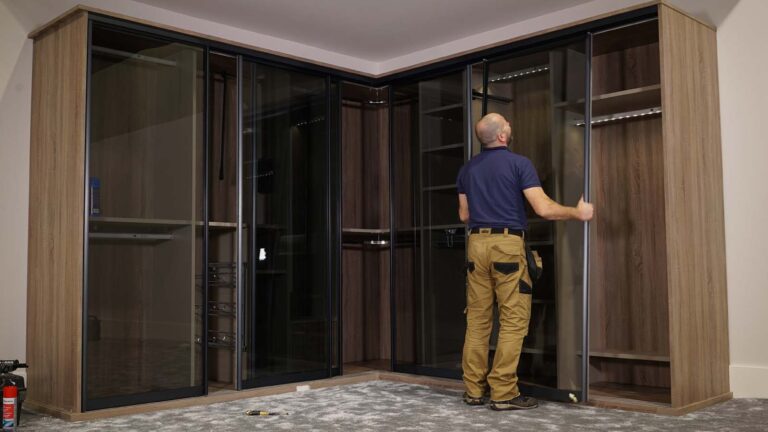 fitter putting on a glass door on a sliding wardrobe